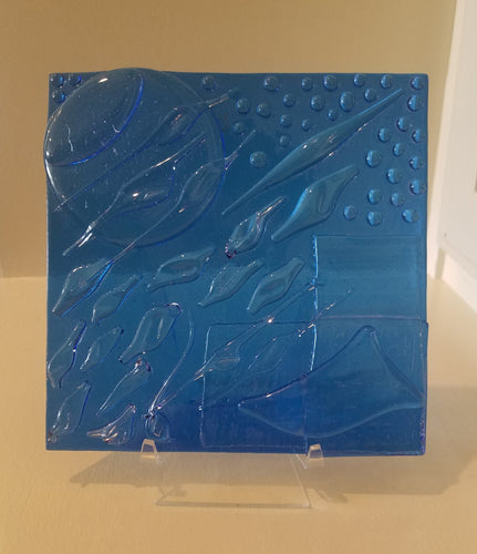 A beautiful hand-crafted decorative glass plate in blue with a flowing abstract artful design. Dimensions: 5-3/4