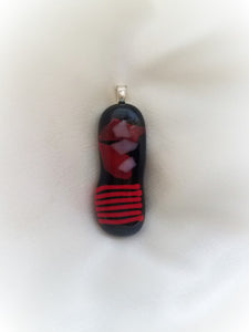 Beautiful red designs on a black glass pendant, approximately 1-6/8" long by 1/2" wide.  Stylish and unique.