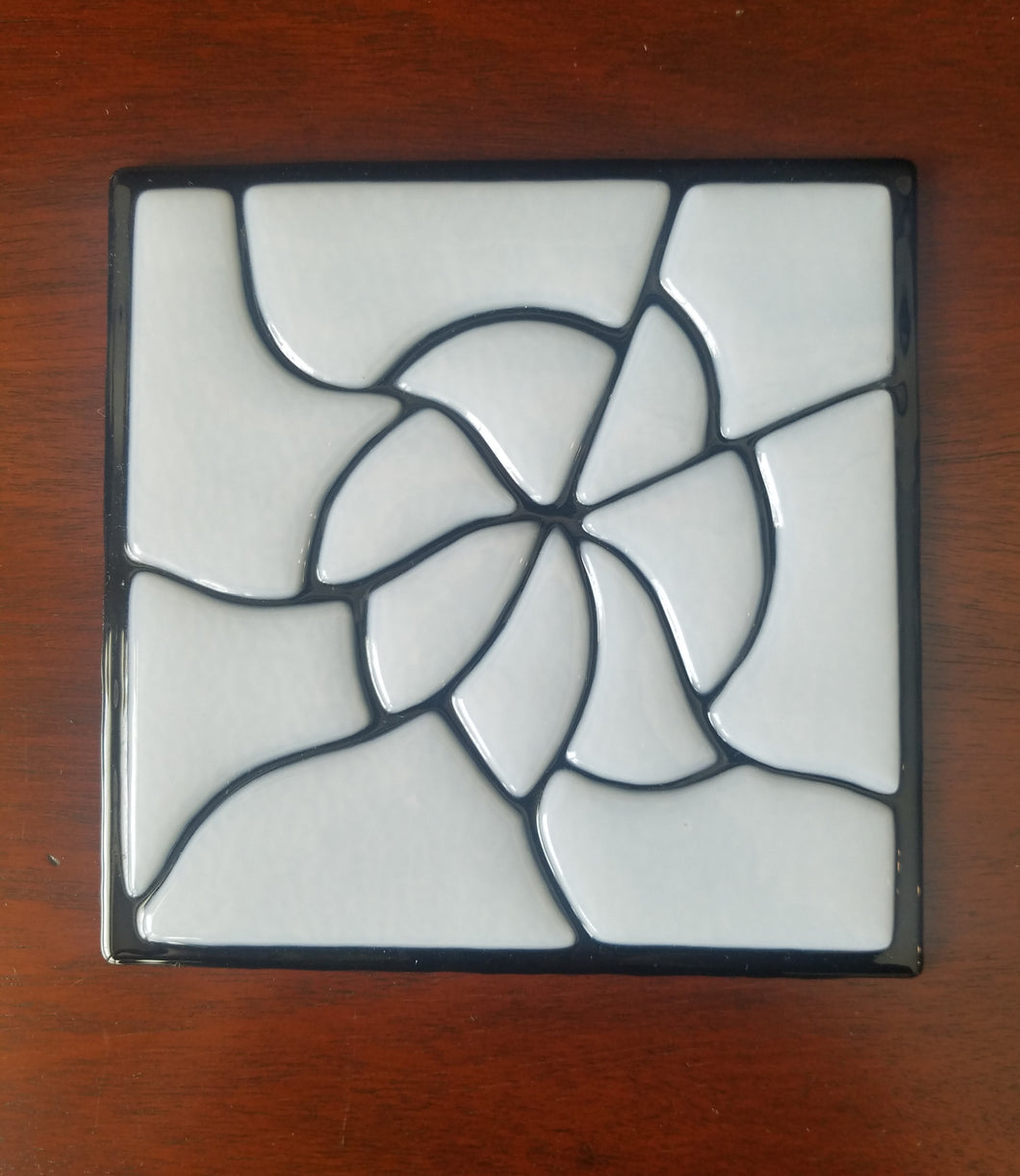 A beautiful hand-crafted decorative glass plate in a black and white petals  design.  Dimensions: 5-3/4